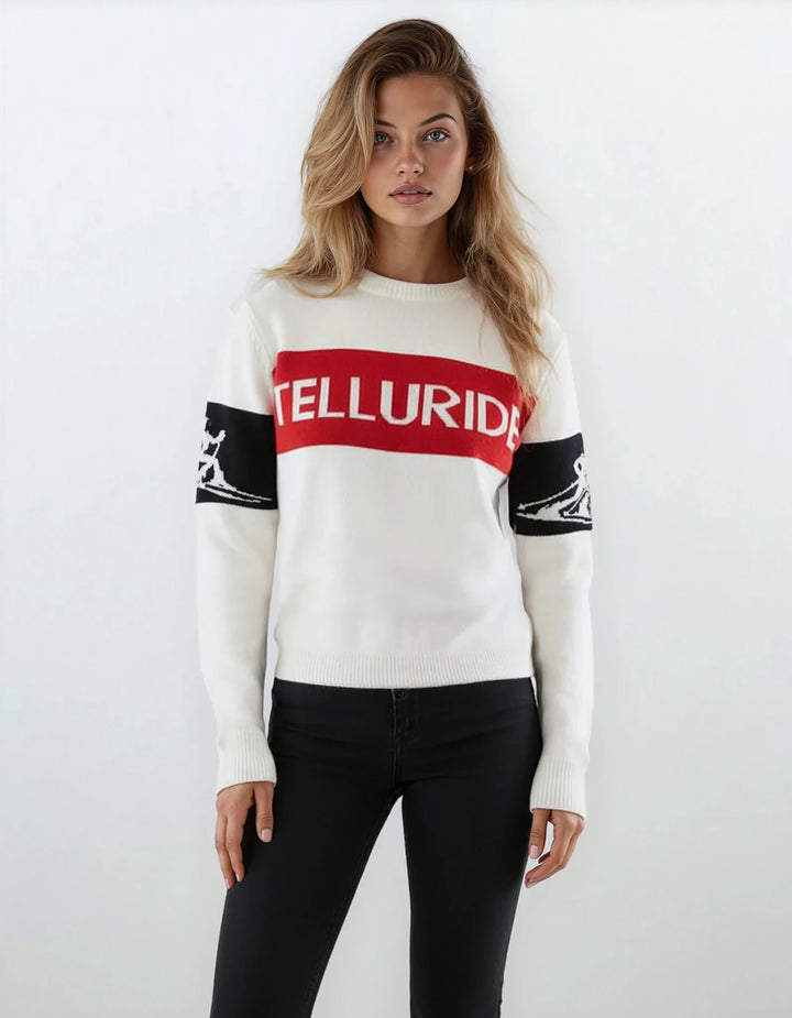Model wearing Denimaxx Women’s relaxed Telluride ski sweater in white, red, and black with bold “Telluride” front knit