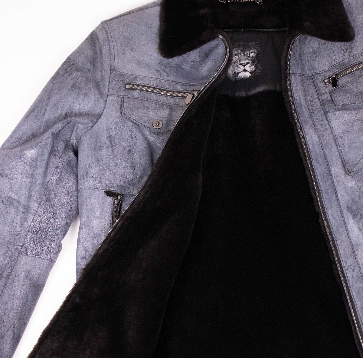 Close-up of the open leather jacket revealing the plush black shearling lining and lion emblem on the inner label.