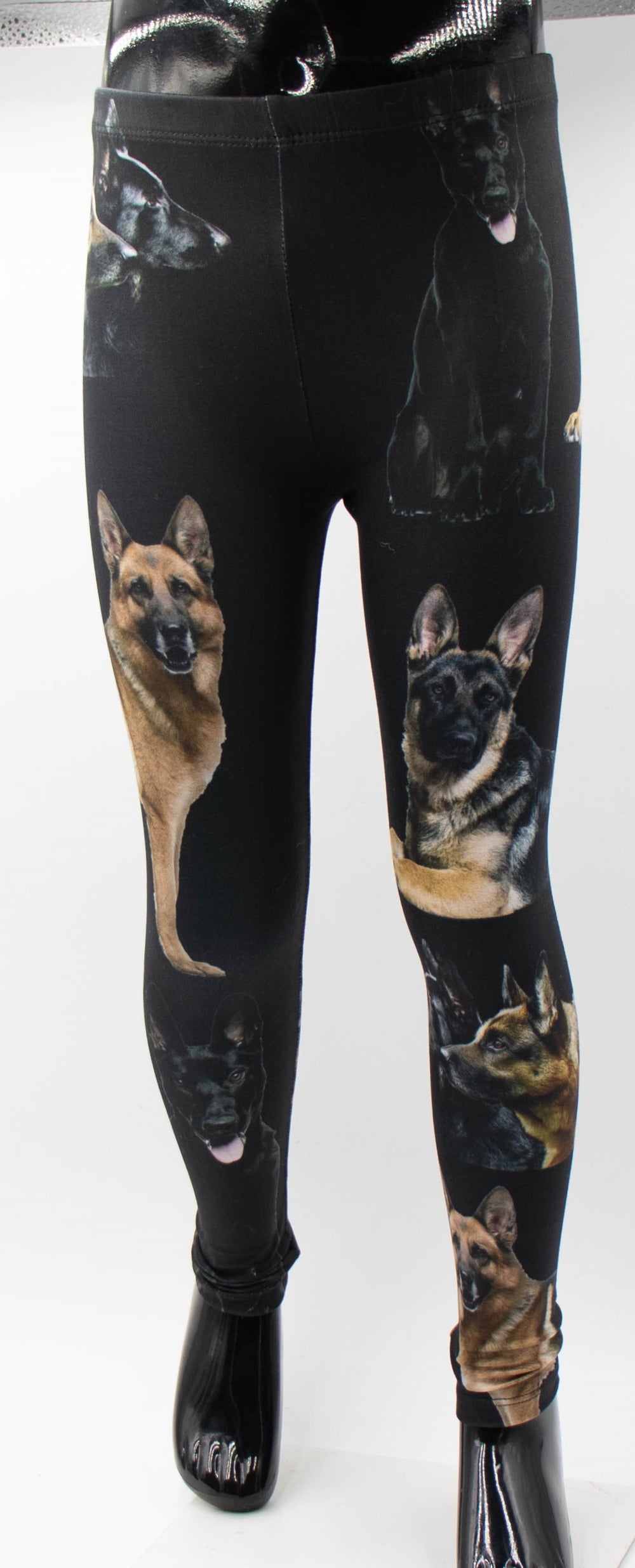 Close-up of Denimaxx kids German Shepherd print leggings on a mannequin, tan and black shepherd portraits on black fabric.