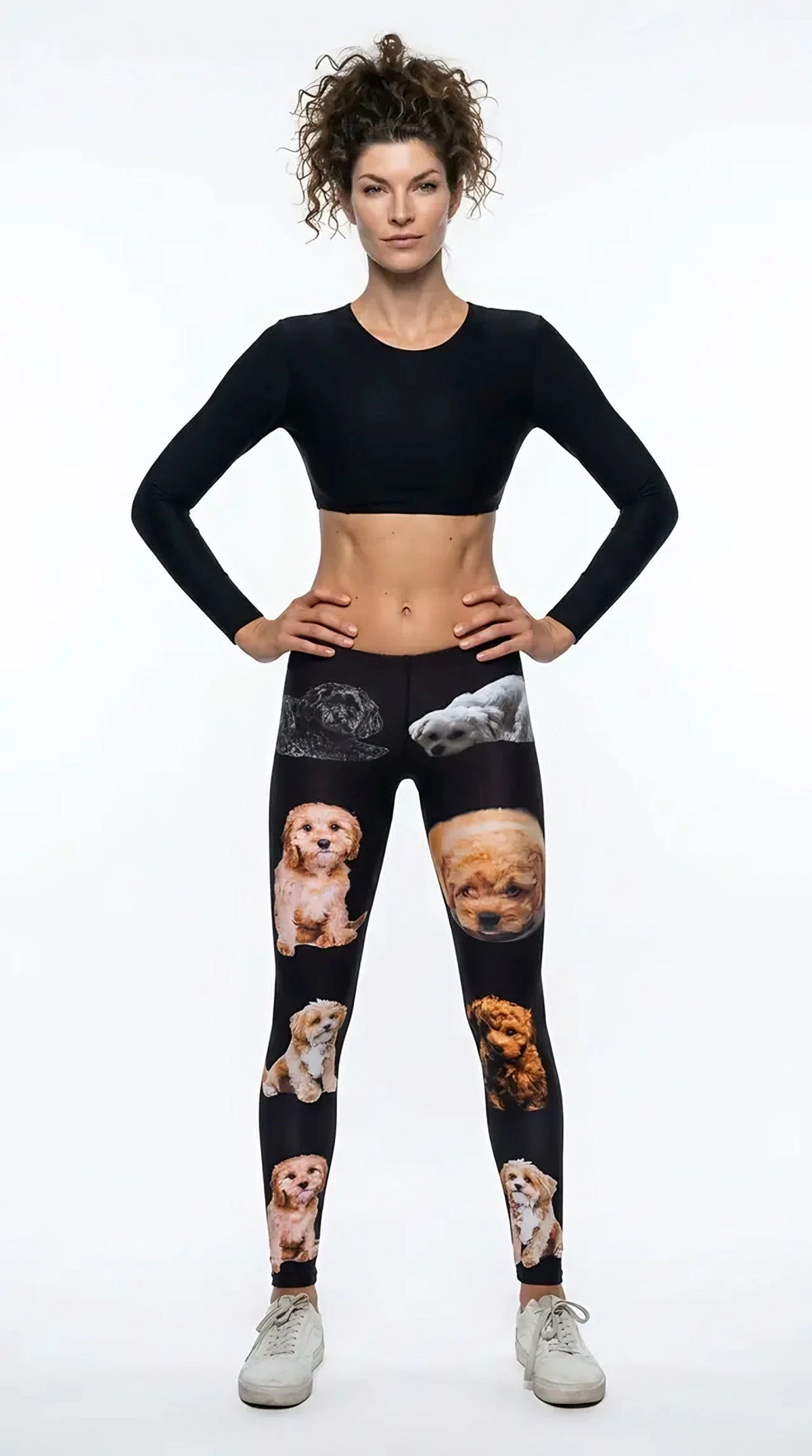 Woman in a black long-sleeve crop top and sneakers wearing black cavapoo puppy print leggings