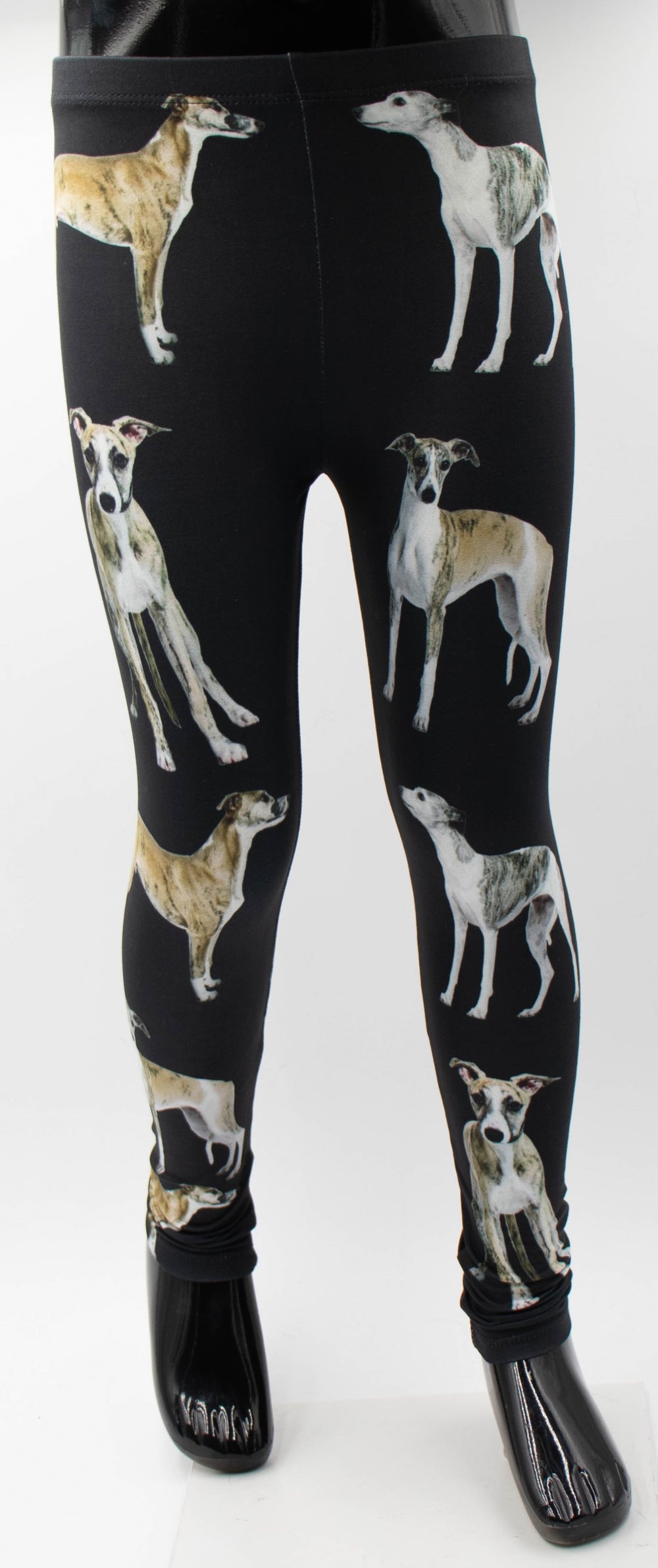 Close-up of Denimaxx kids Whippet print leggings on a mannequin, tan and brindle whippet portraits on black fabric.