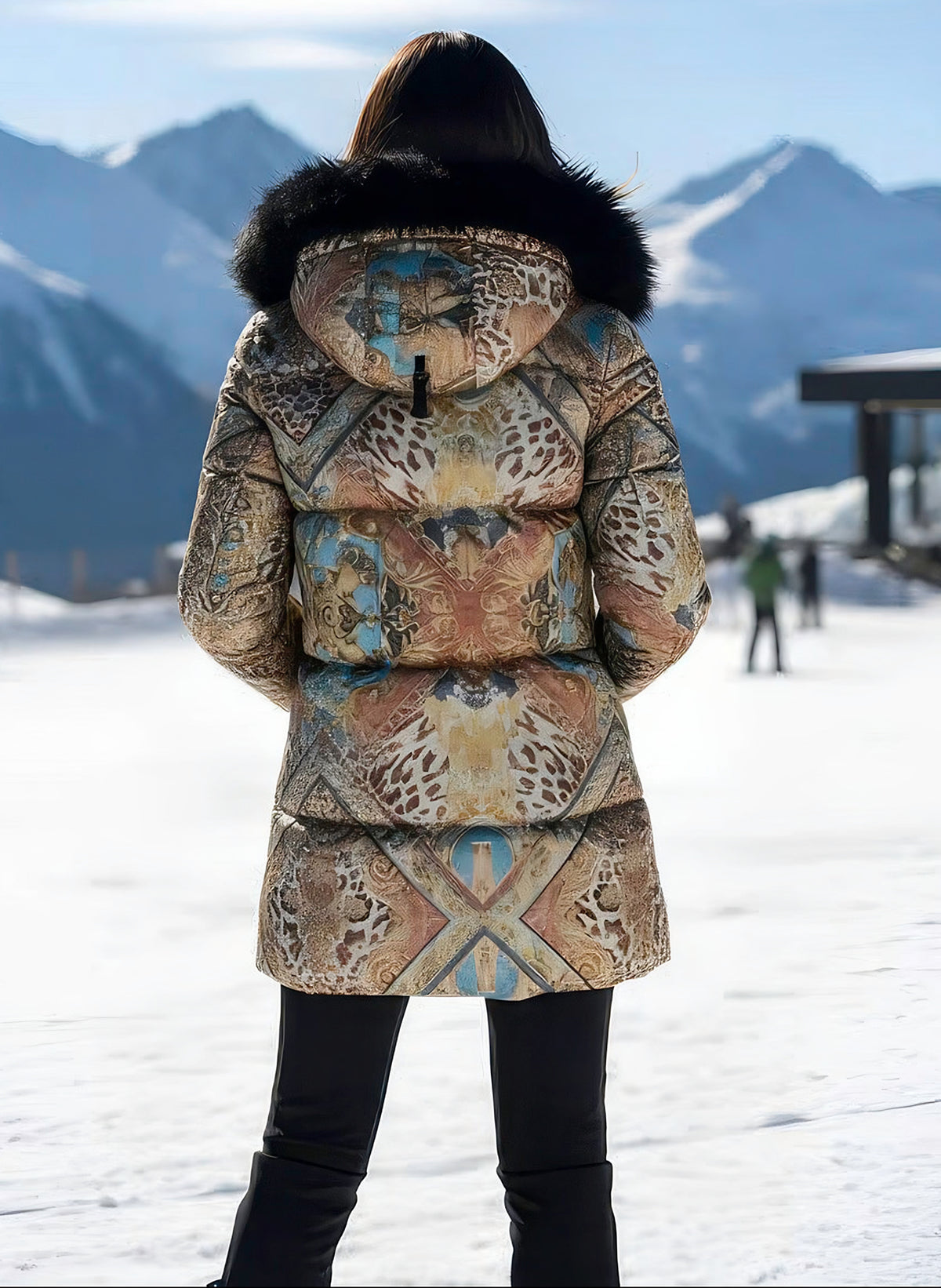 Back view of woman wearing the patchwork satin down coat with black fox fur hood, snowy mountains behind.