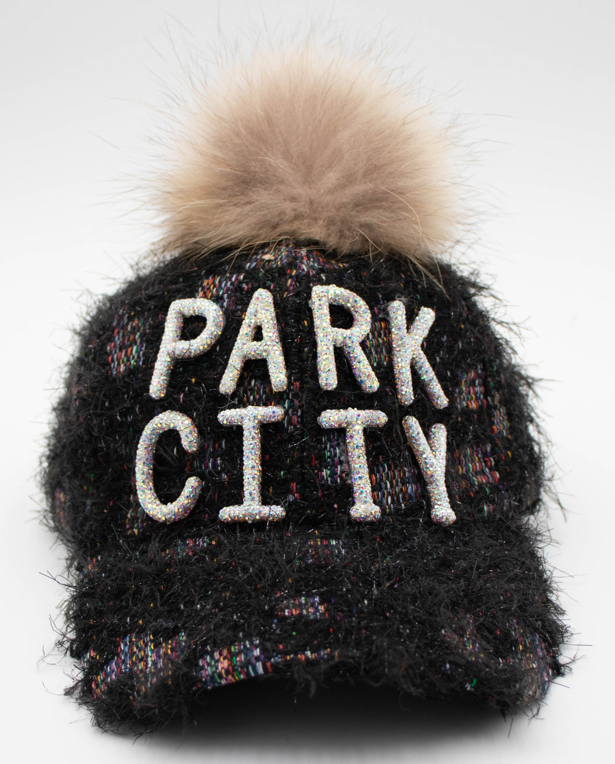 Front view of the Crystal Park City baseball cap with crystal PARK CITY lettering and a tan faux fur pom on black fuzzy tweed.