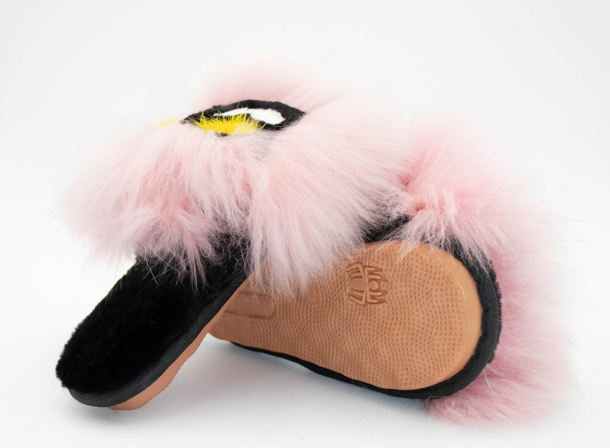 Pink fox fur slide slippers showing the tan rubber outsole with embossed logo, plush pink fur top.