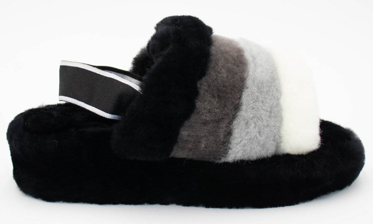 Side view of the black sheepskin slide slipper with gray and white striped strap and black heel band with white trim.
