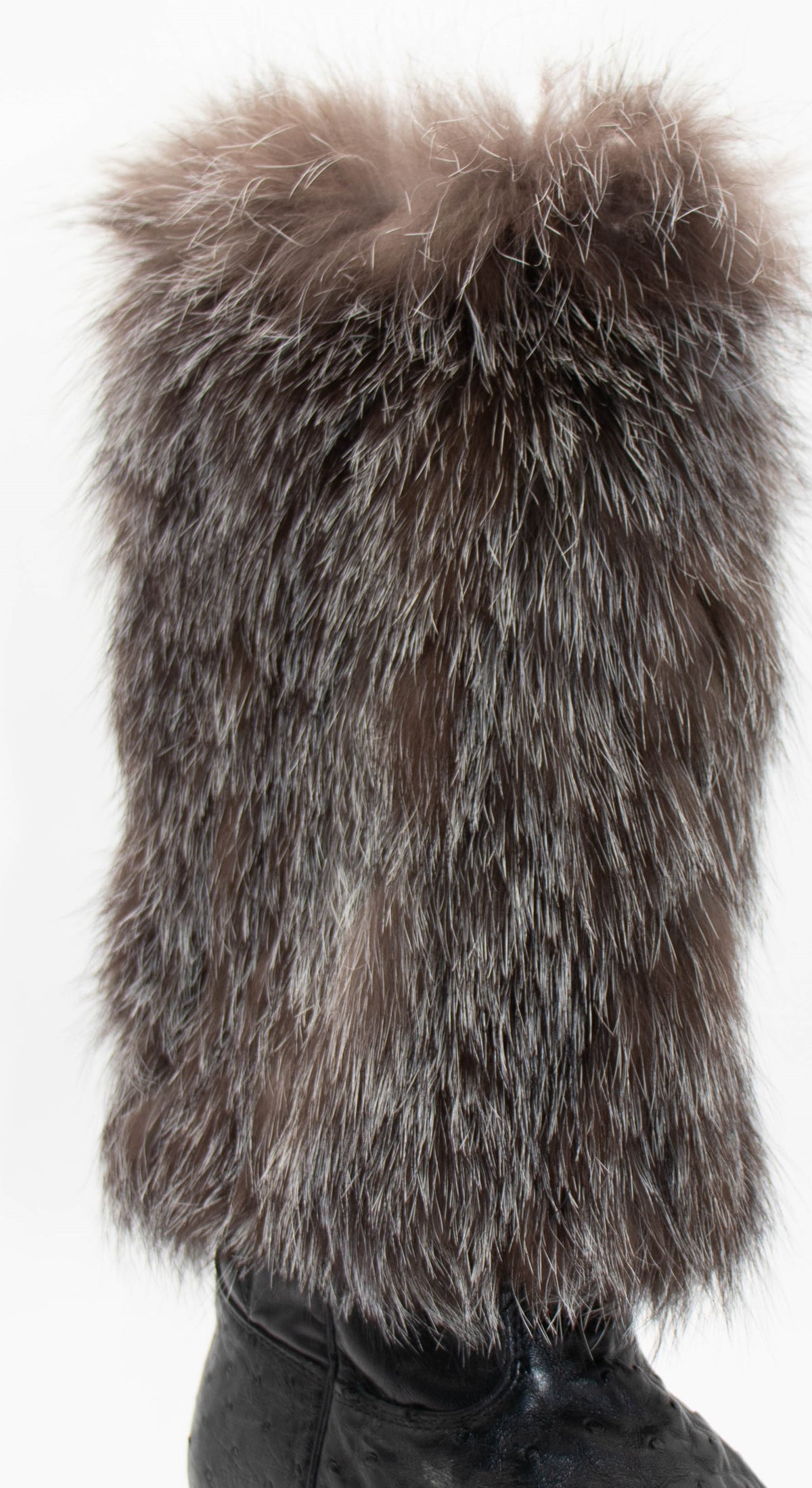 Close-up of the gray fox fur leg warmer on a black boot, showing the thick silver-tipped fur, on white.