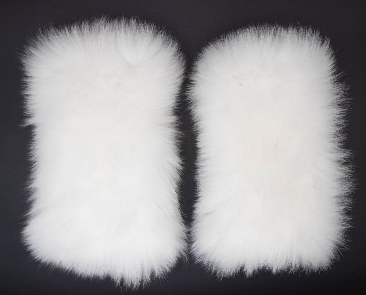 Pair of white fox fur leg warmers laid flat, showing the plush white fur texture, on a dark background.