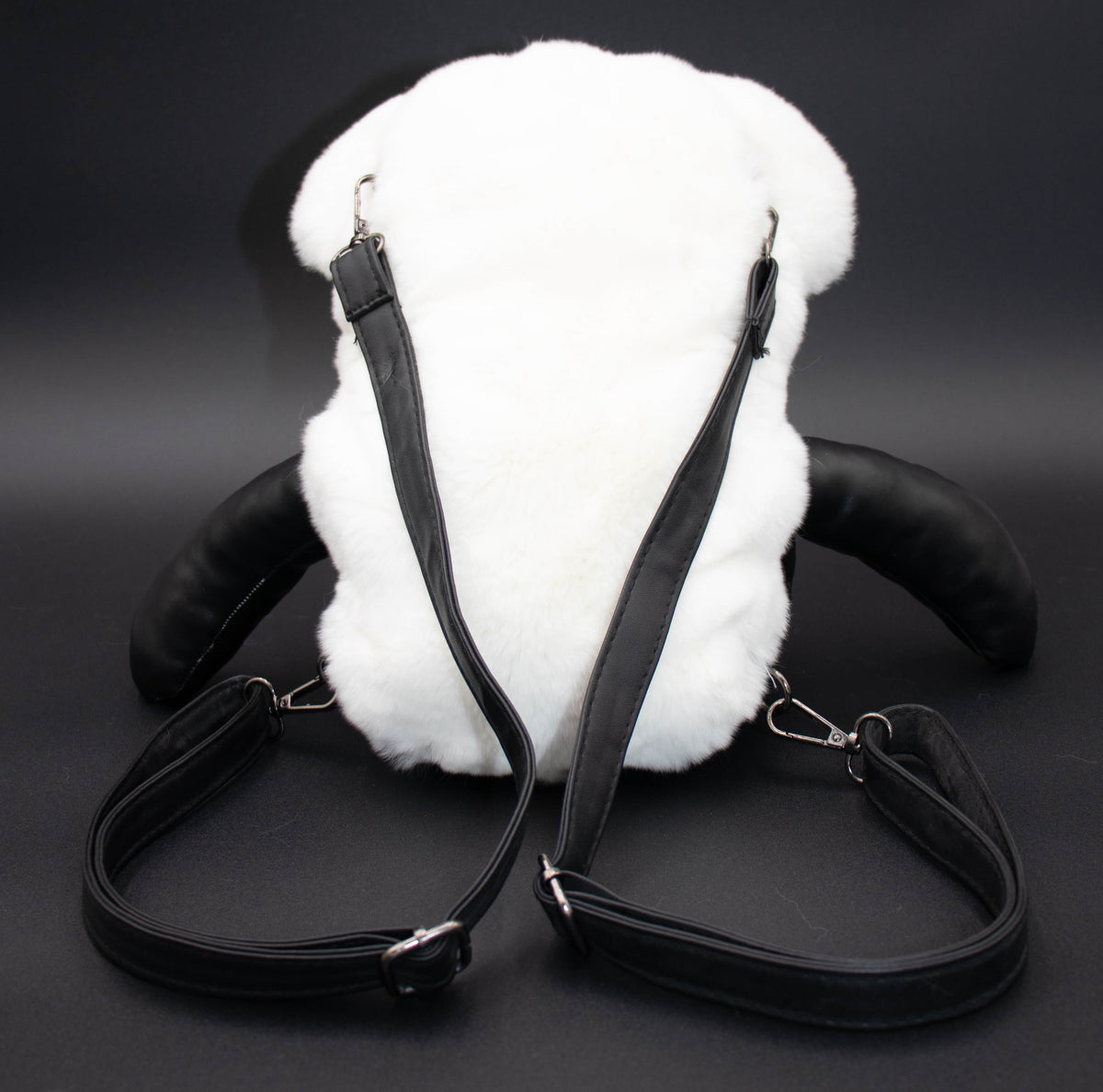 Back view of the white rex rabbit fur bear backpack showing adjustable black shoulder straps, studio shot.