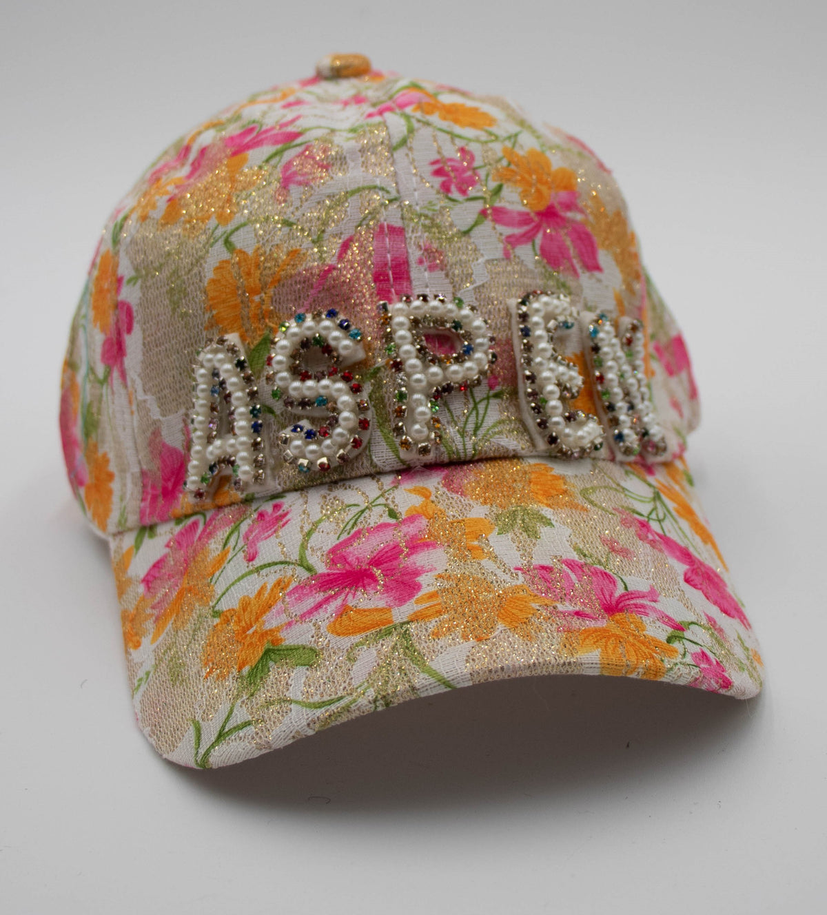 Pearl-Detail Aspen baseball cap with pearl and crystal ASPEN lettering over pink and orange floral lace, front view on white.