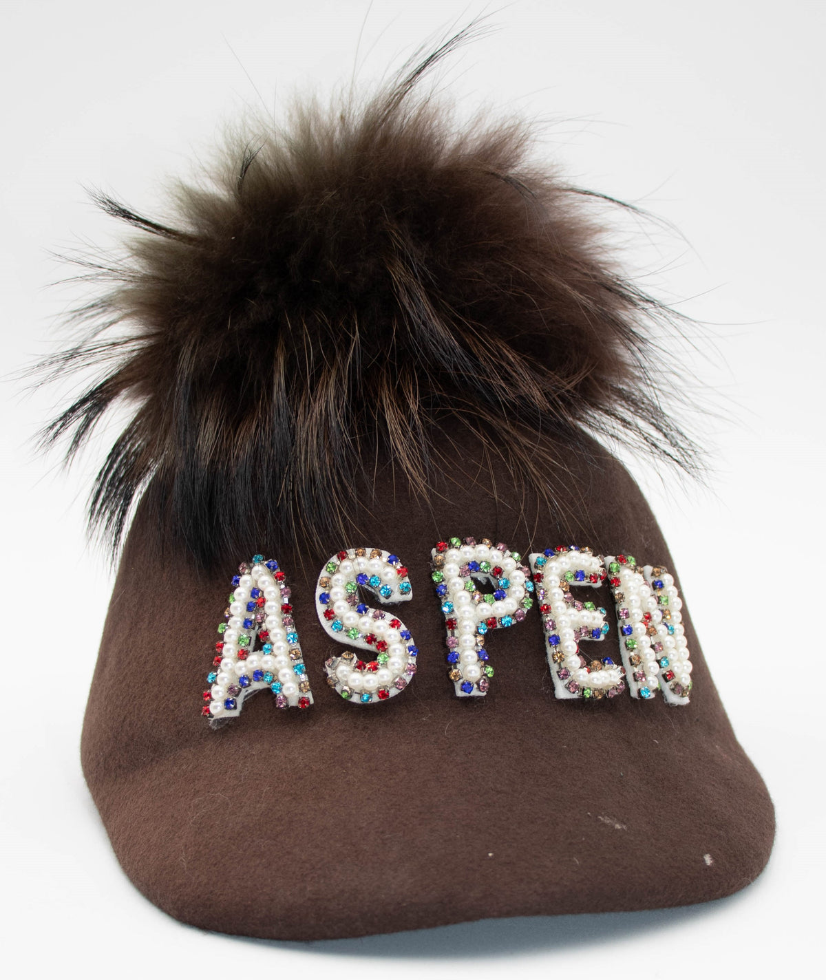Aspen Pearl brown cap with pearl-beaded ASPEN letters and a dark faux fur pom, product shot on white.