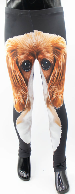 Kids King Charles print leggings with a giant ruby and white cavalier spaniel face wrapping around black fabric, front view on a mannequin.