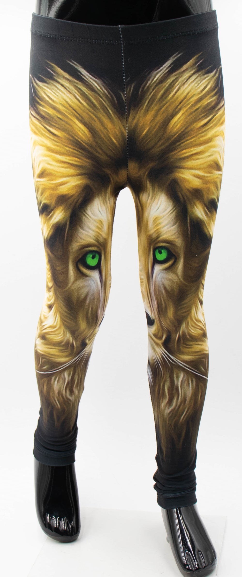 Close-up of Denimaxx kids lion print leggings on a mannequin, golden lion face with green eyes on black fabric.