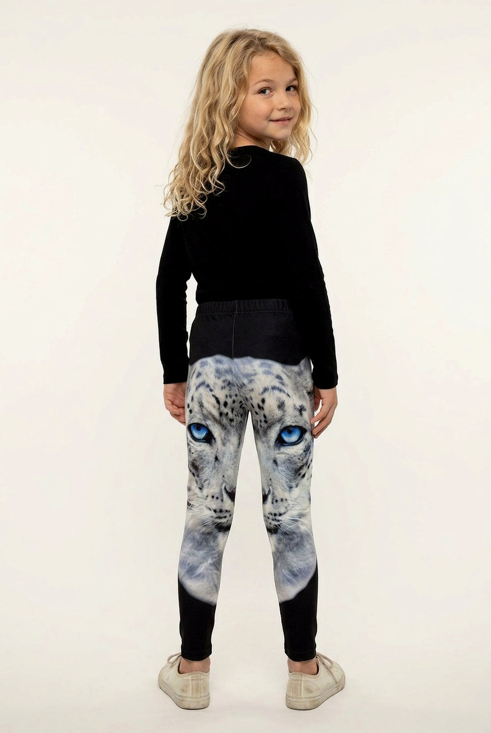 Back view of a girl with long curly hair in snow leopard print girls leggings, solid black below the knee