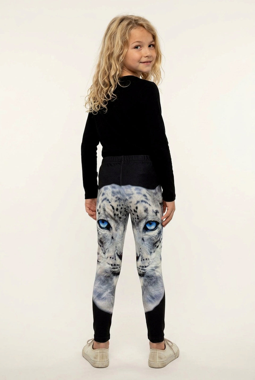 Back view of a girl with long curly hair in snow leopard print girls leggings, solid black below the knee
