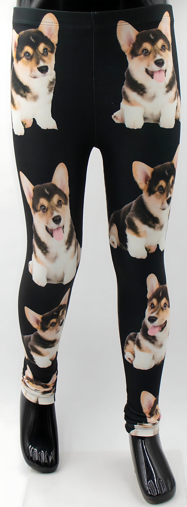 Close-up of kids Corgi print leggings on a mannequin, showing six smiling tricolor corgi puppy graphics on black fabric.