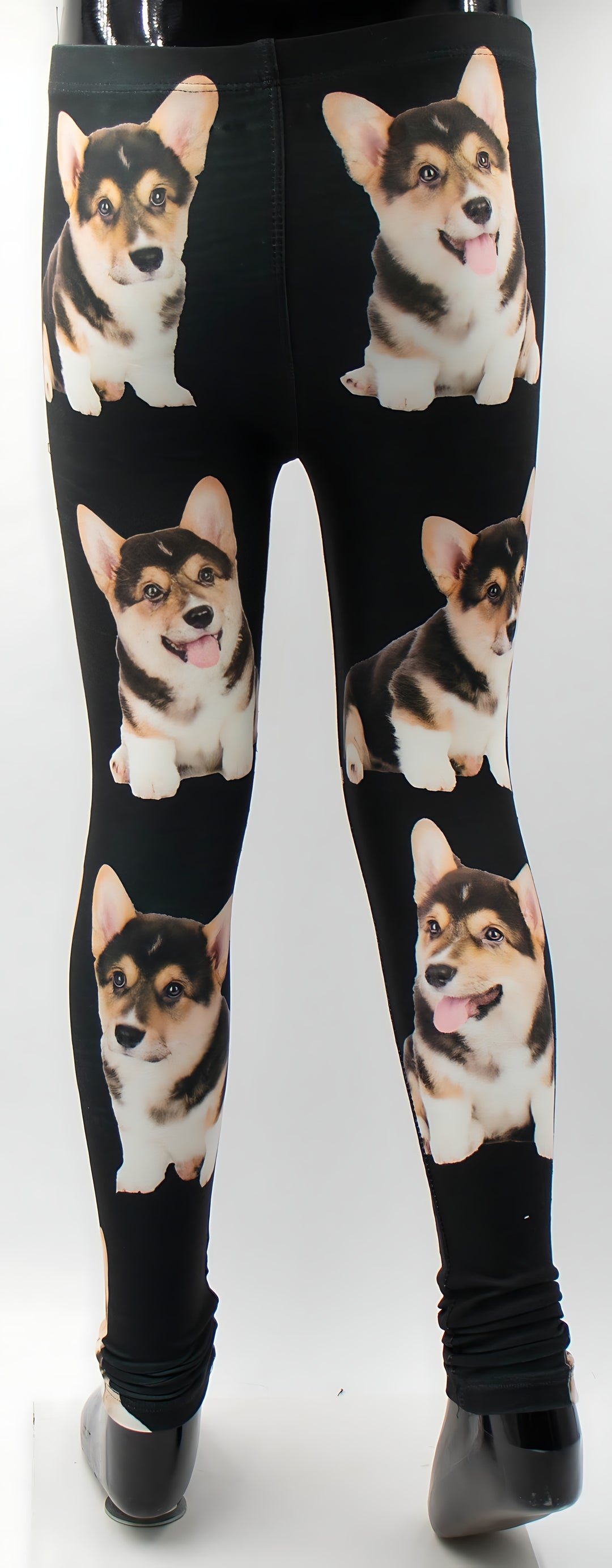 Full-length view of kids Corgi print black leggings on a mannequin, all-over pattern of six tricolor corgi puppies.