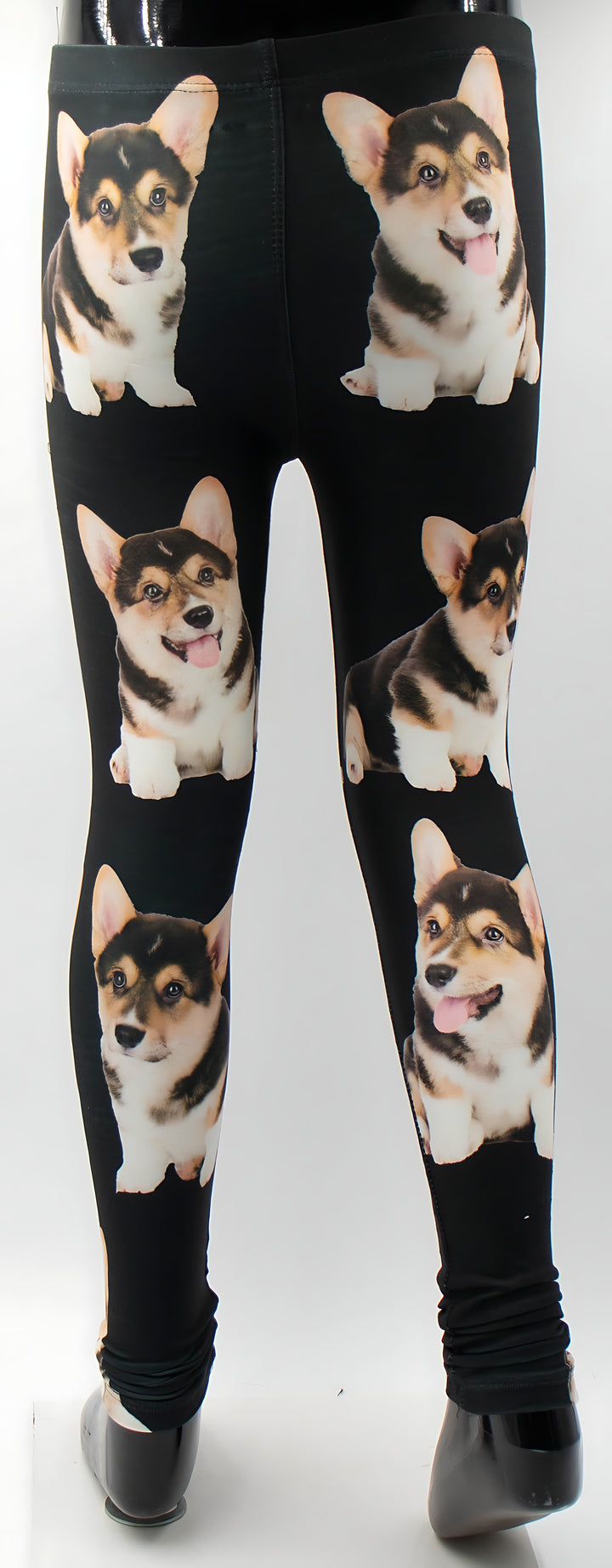 Full-length view of kids Corgi print black leggings on a mannequin, all-over pattern of six tricolor corgi puppies.