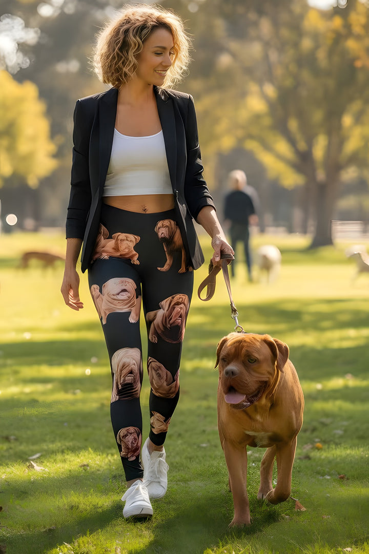 Woman in a black blazer wearing Dogue de Bordeaux print leggings, walking a real Dogue de Bordeaux on a leash at the park.