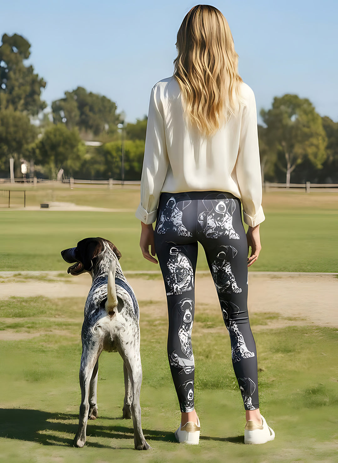 Back view of woman wearing German Shorthaired Pointer print leggings with a real German Shorthaired Pointer beside her at the park.