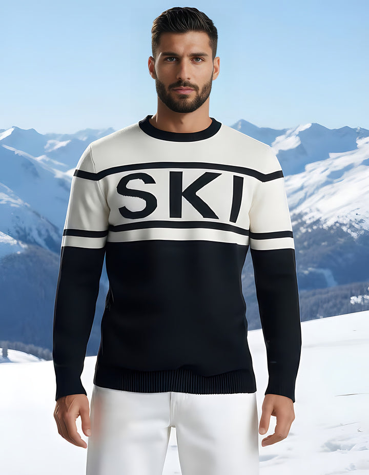 Close-up of the SKI intarsia crewneck sweater with bold black lettering on a white chest band, modeled in the snow.