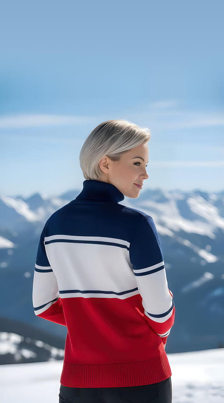 Back view of the red, white and navy Cowgirl Ski turtleneck sweater with striped knit bands, modeled on a snowy mountain.