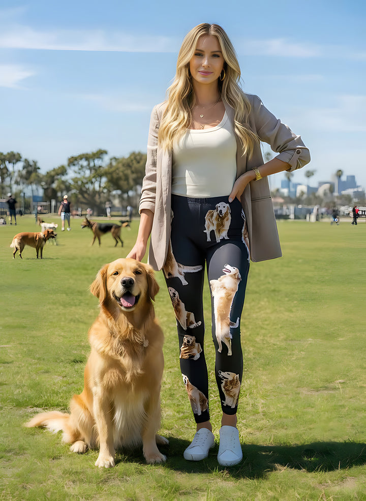 Woman in a beige blazer wearing Golden Retriever print leggings with golden portraits, standing beside a real Golden Retriever at the park.