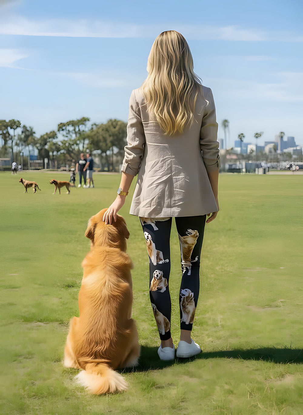 Back view of woman in a beige blazer wearing Golden Retriever print leggings, resting her hand on a real Golden Retriever in a grassy park.