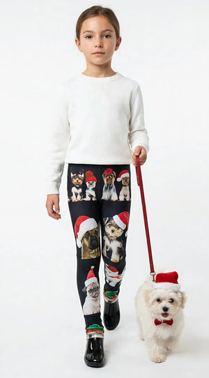 Young girl holding a leash with a small white dog in a Santa hat, wearing kids Christmas dogs print leggings and a white sweater.