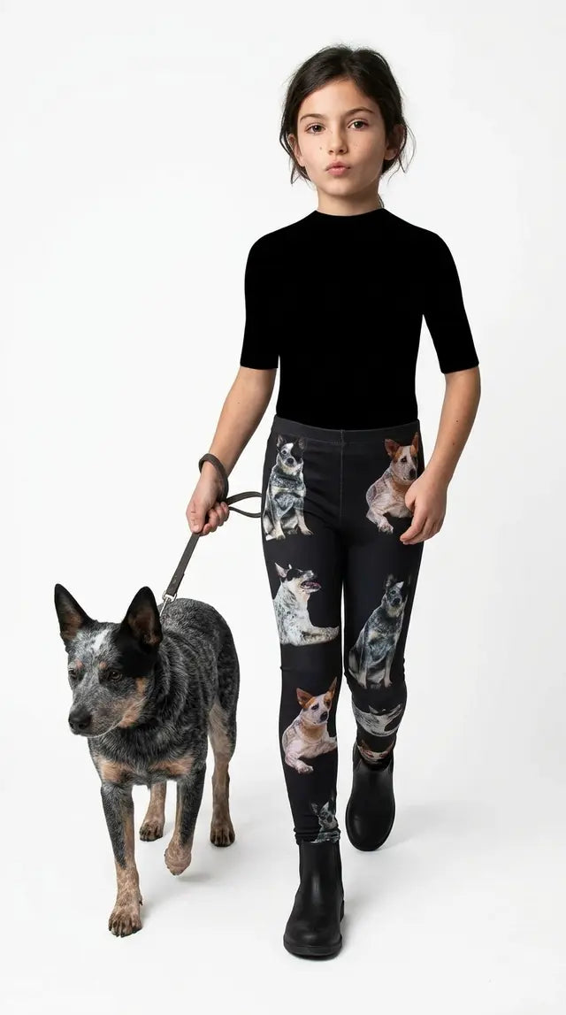 Girl in a black tee and white sneakers walking an Australian Cattle Dog on a leash, wearing black kids leggings with an Australian Cattle Dog print
