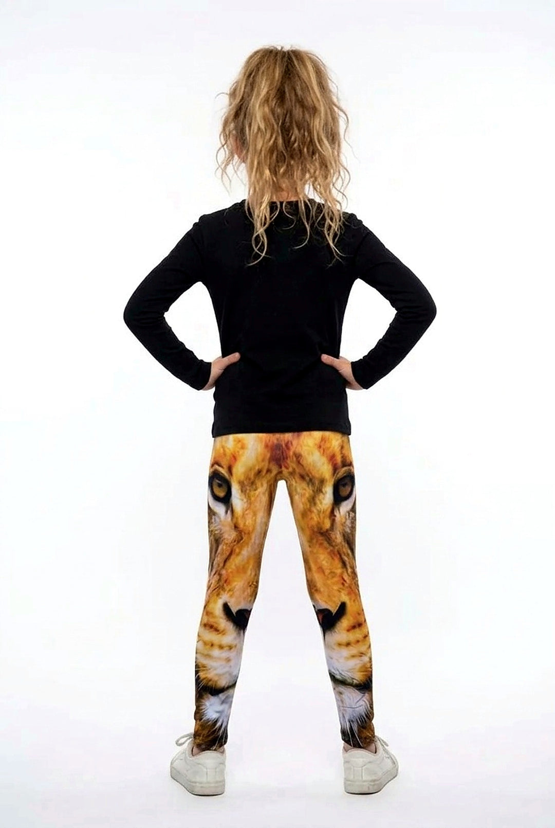 Back view of a girl with curly hair wearing all-over golden lion face print girls leggings
