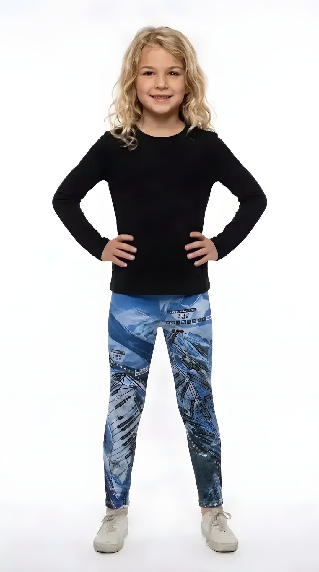 Smiling girl in a black long-sleeve top and white sneakers wearing blue Aspen Trail Map print girls leggings