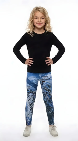 Smiling girl in a black long-sleeve top and white sneakers wearing blue Aspen Trail Map print girls leggings
