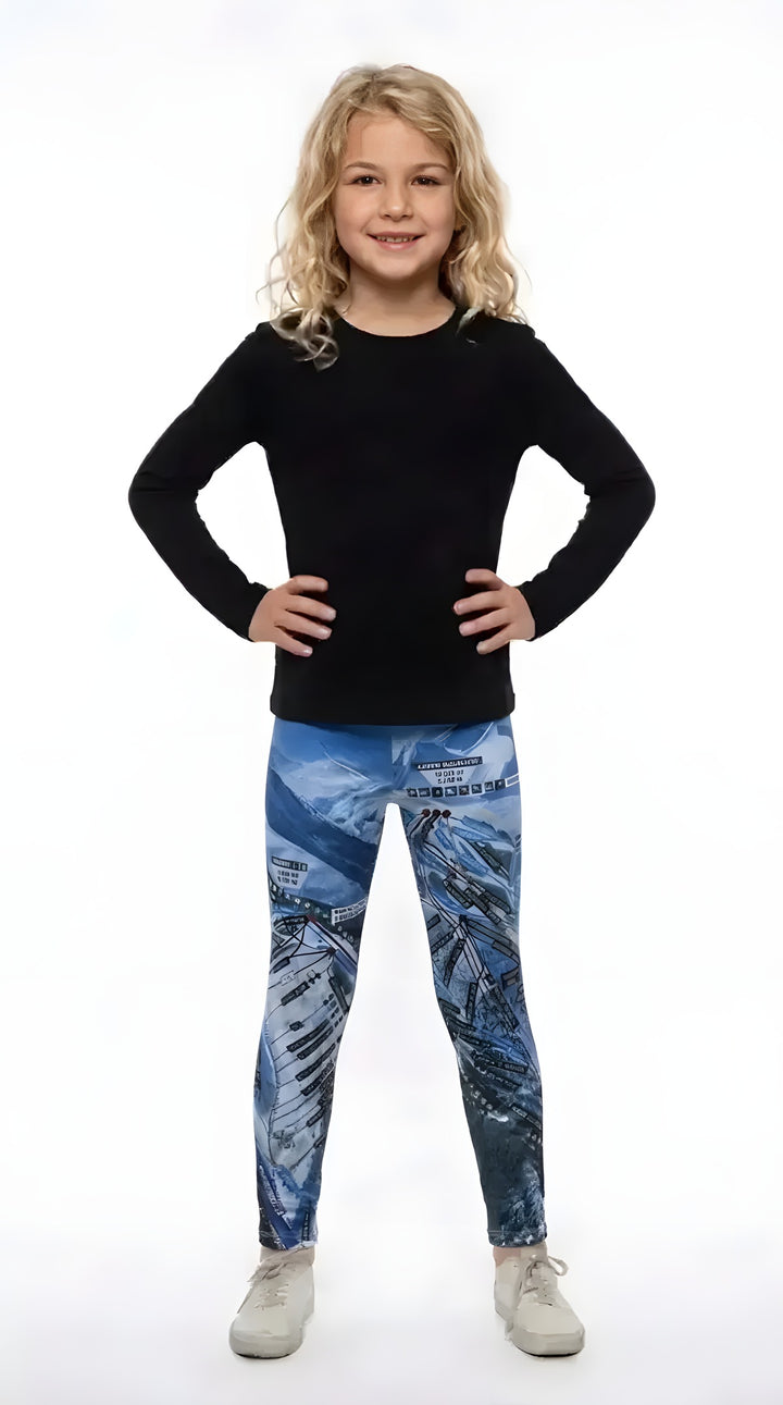 Smiling girl in a black long-sleeve top and white sneakers wearing blue Aspen Trail Map print girls leggings