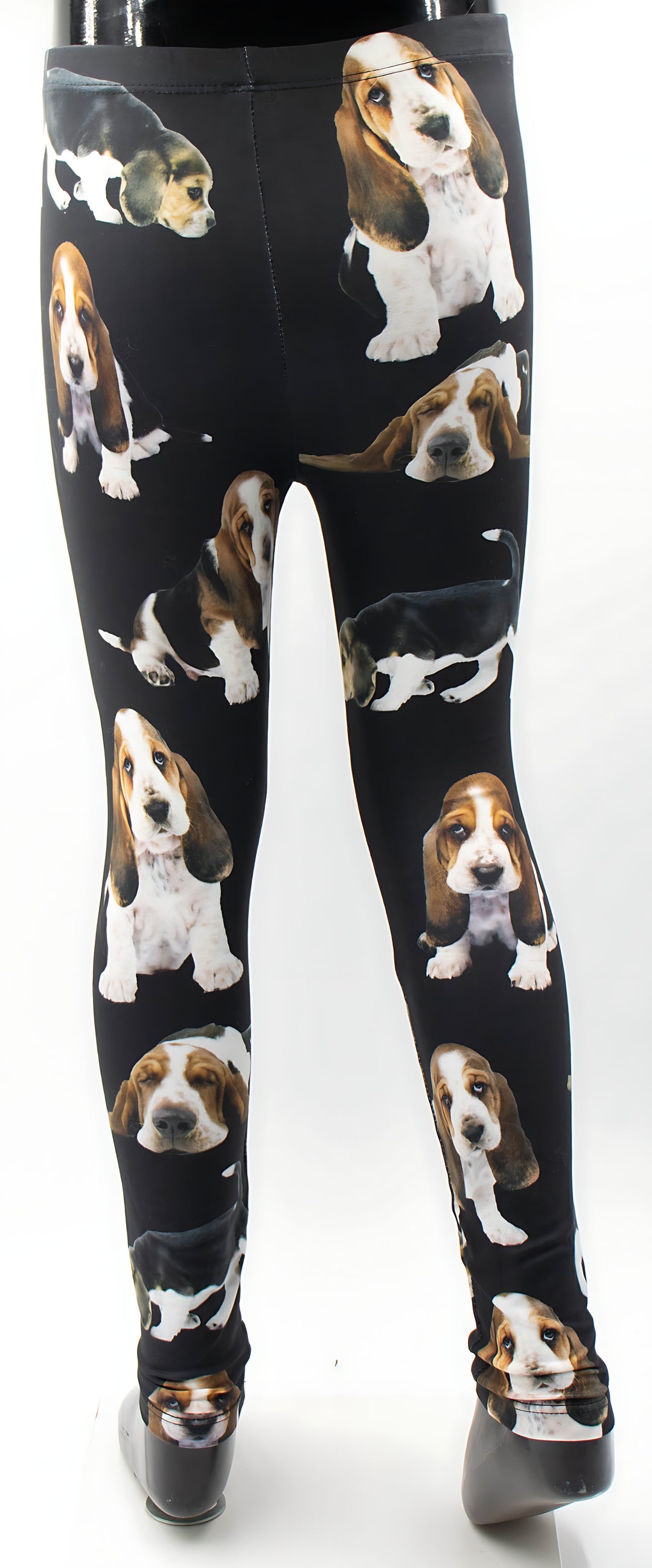 Front view of kids Basset Hound print leggings with scattered Basset Hound puppy prints on black, shown on a child mannequin.