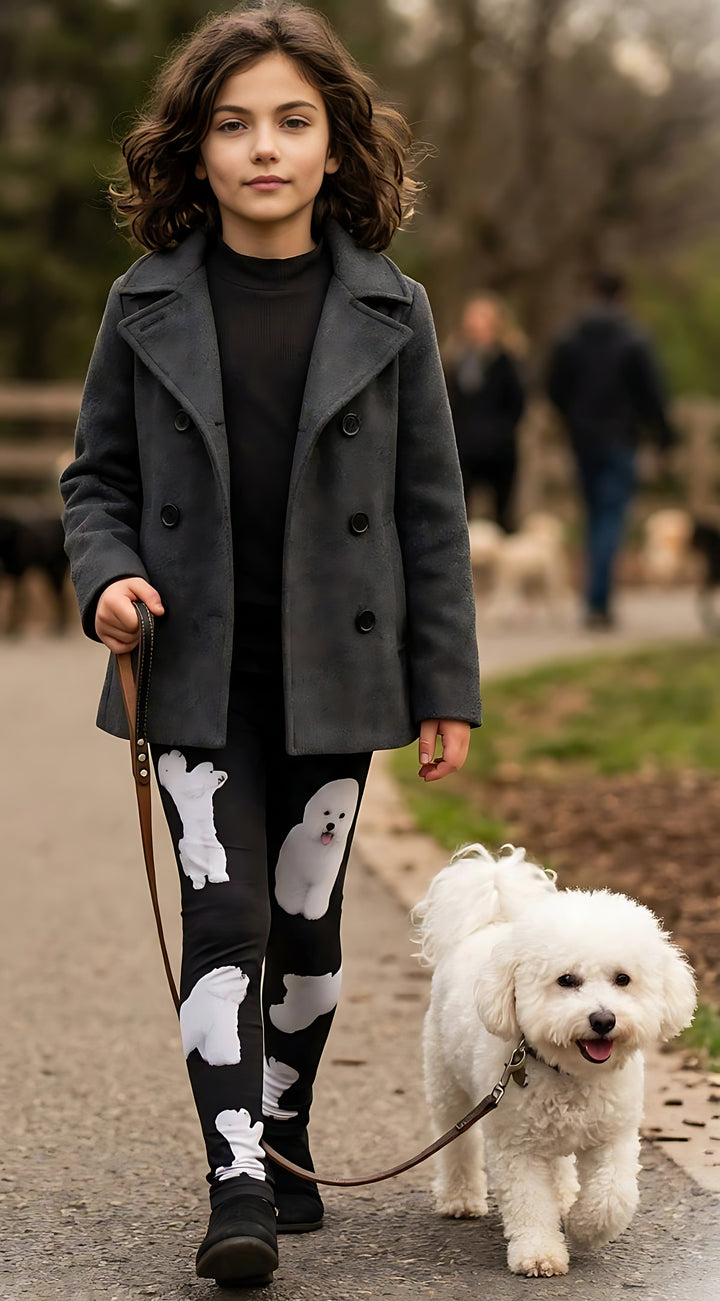 Young girl walking a real white Bichon Frise on a leash outdoors, wearing kids Bichon print leggings with white dog prints, gray coat.