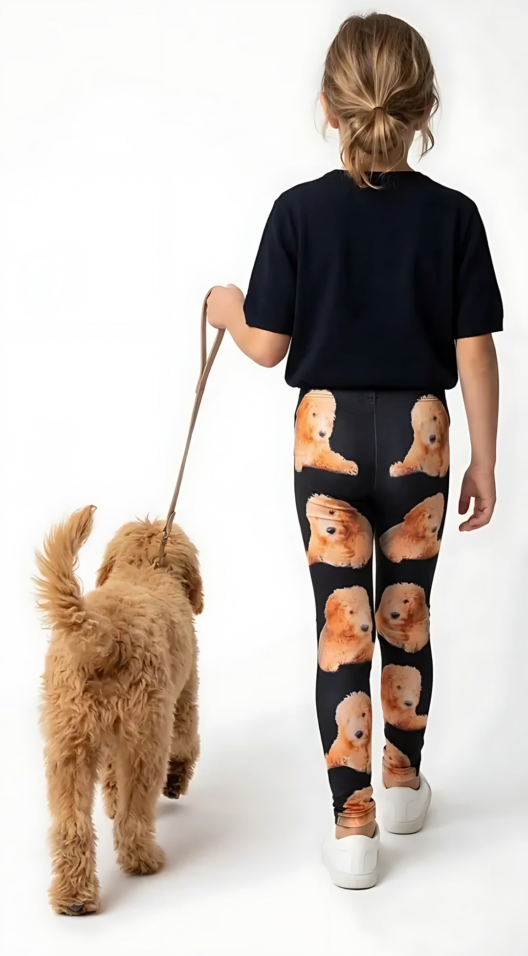 Back view of a girl in a navy tee walking a Goldendoodle, wearing black Goldendoodle print girls leggings