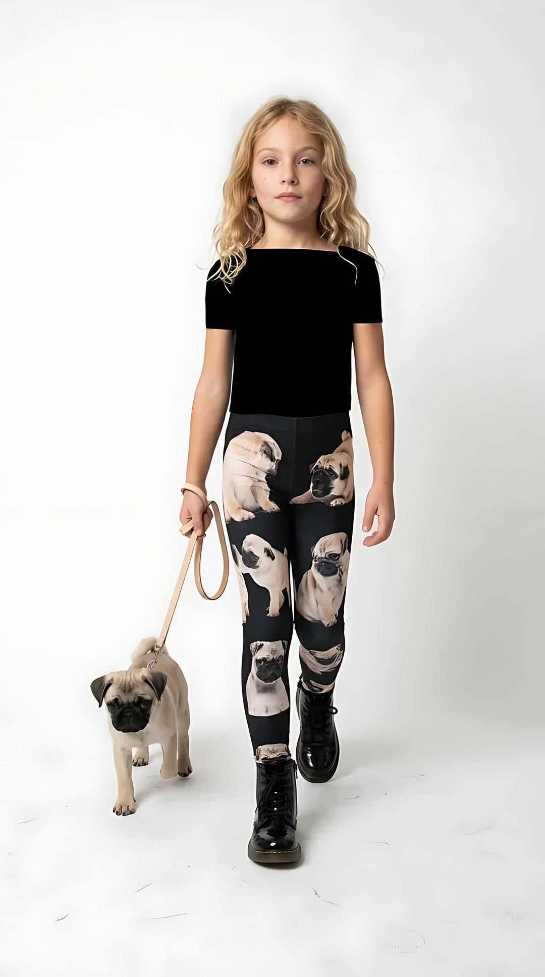Girl in a black tank top posing with a Pug puppy, wearing black kids leggings with an all-over Pug print on a bright indoor background