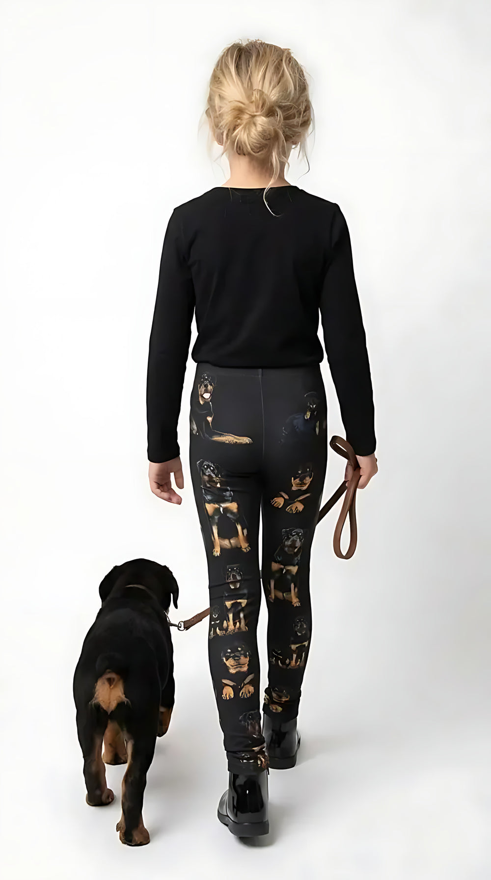 Back view of a girl walking a Rottweiler puppy, wearing black Rottweiler print girls leggings