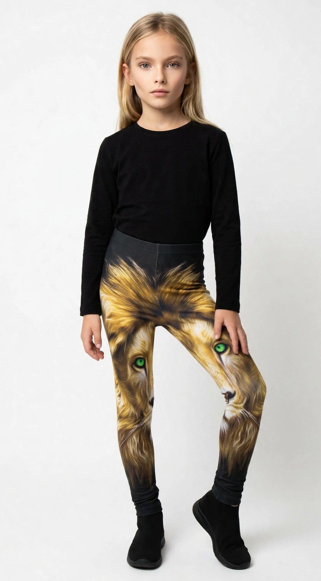 Young girl wearing Denimaxx kids lion print leggings with a golden lion face and green eyes, black top and shoes.