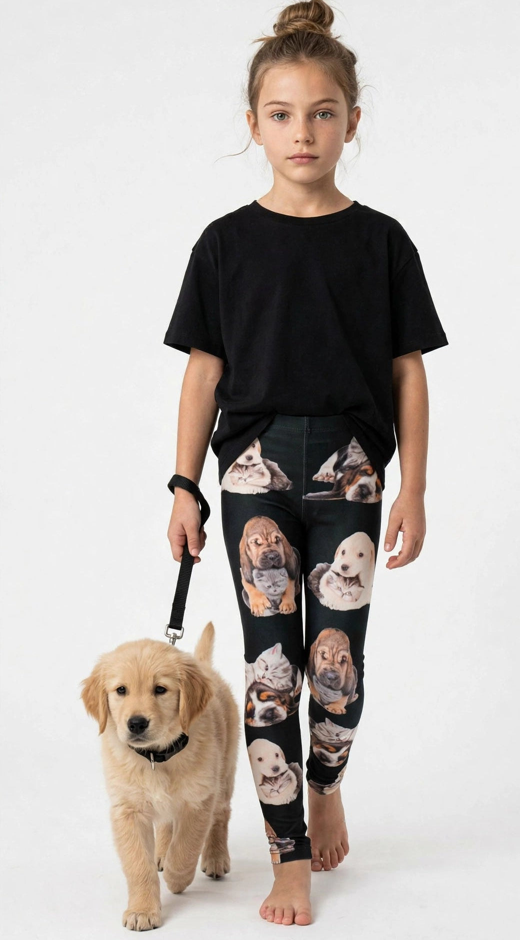Young girl with a top knot wearing Denimaxx kids kitten and puppy print leggings with cuddling pet artwork, holding a leash with a real golden retriever puppy.