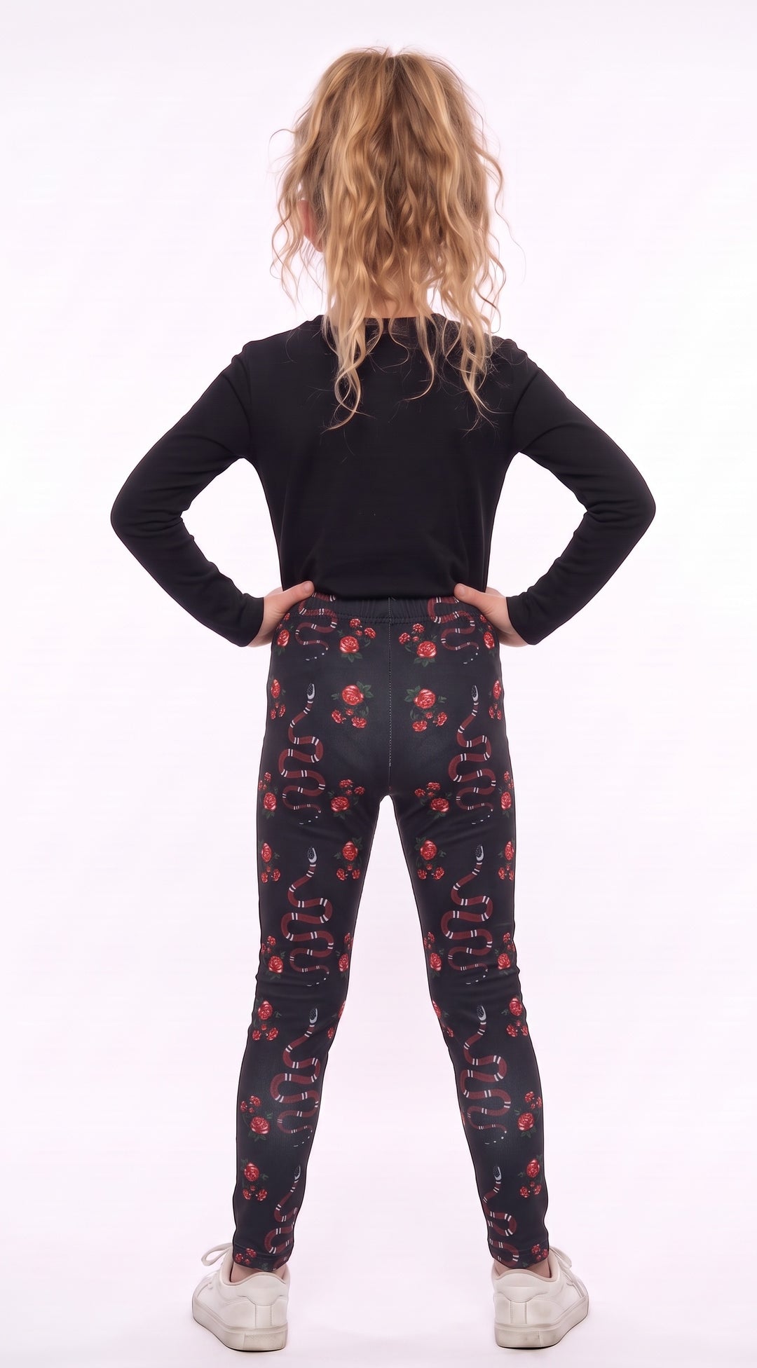 Girl wearing black leggings with red snakes and roses, back view