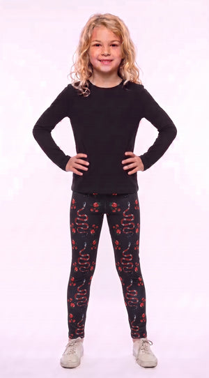 Girl wearing black leggings with red snakes and roses, front view