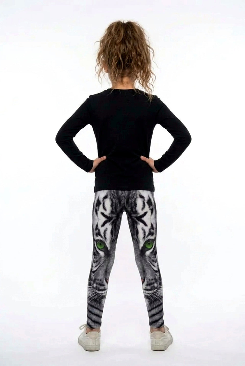 Back view of a girl in a black long-sleeve top wearing all-over white tiger print girls leggings