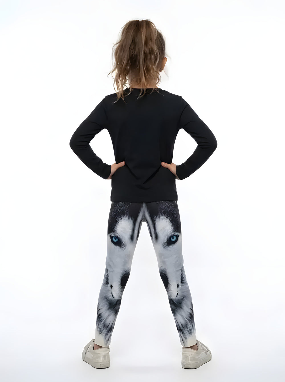 Back view of a girl in a black top wearing black, white and gray wolf face print girls leggings with blue eyes