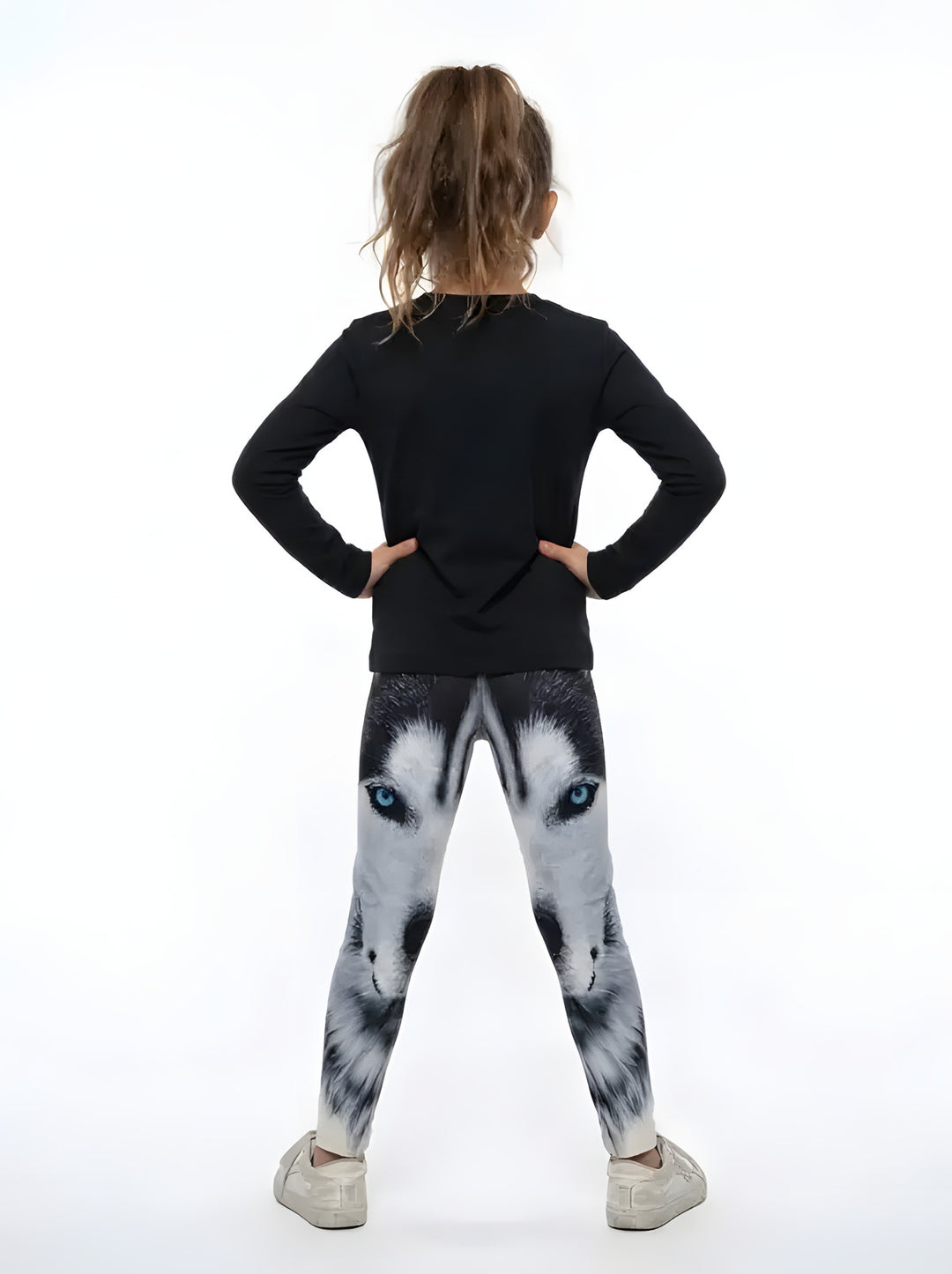 Back view of a girl in a black top wearing black, white and gray wolf face print girls leggings with blue eyes