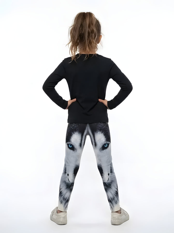 Back view of a girl in a black top wearing black, white and gray wolf face print girls leggings with blue eyes
