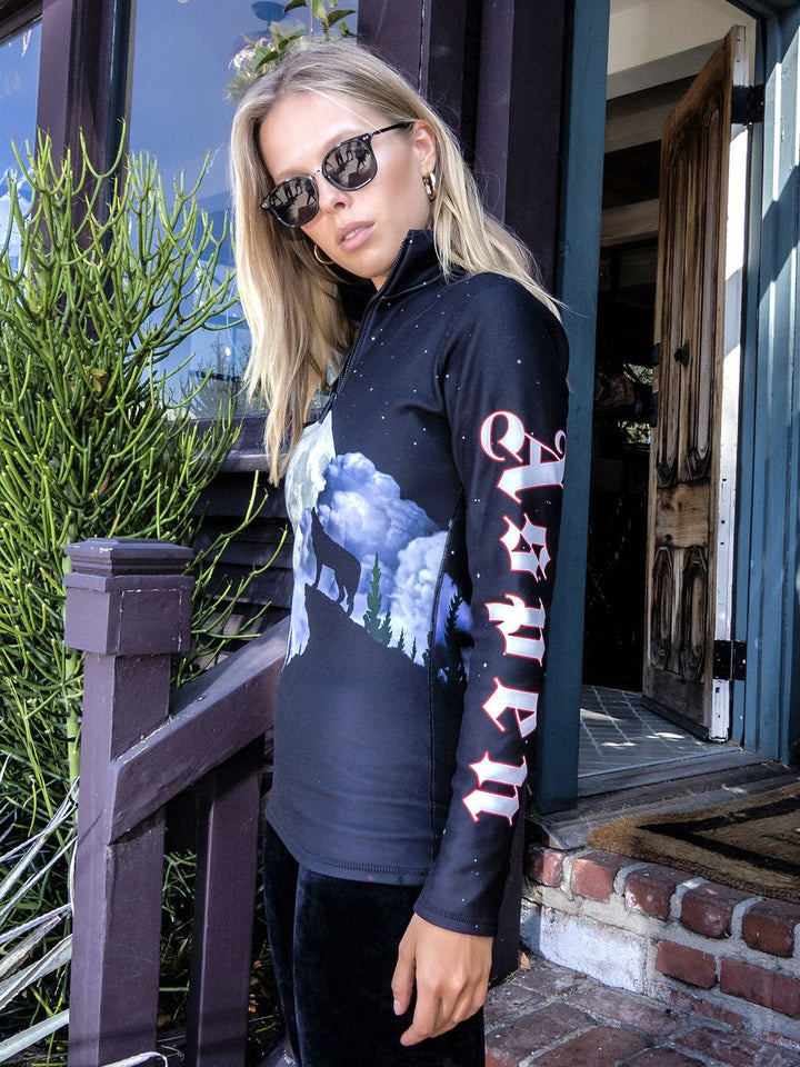 Side view of woman wearing the Howling Wolf mid-layer top with a howling wolf graphic and lettering down the sleeve.