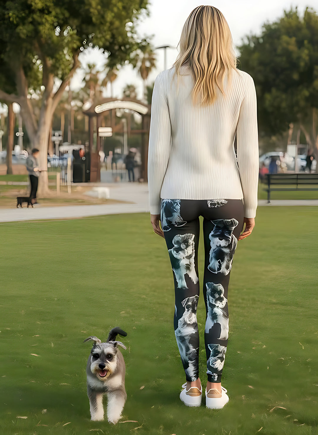Back view of woman wearing Miniature Schnauzer print leggings with a real Schnauzer behind her at the park.