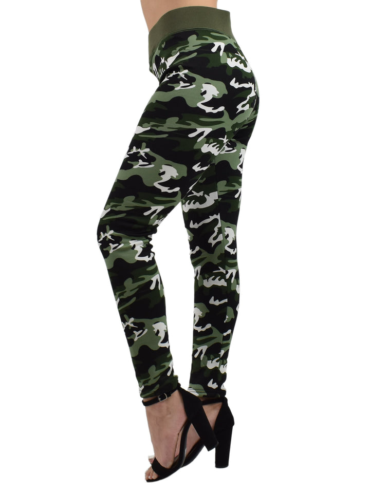 Side view of Denimaxx Northern Woods camo leggings with green woodland print, one leg forward, on a white studio background.