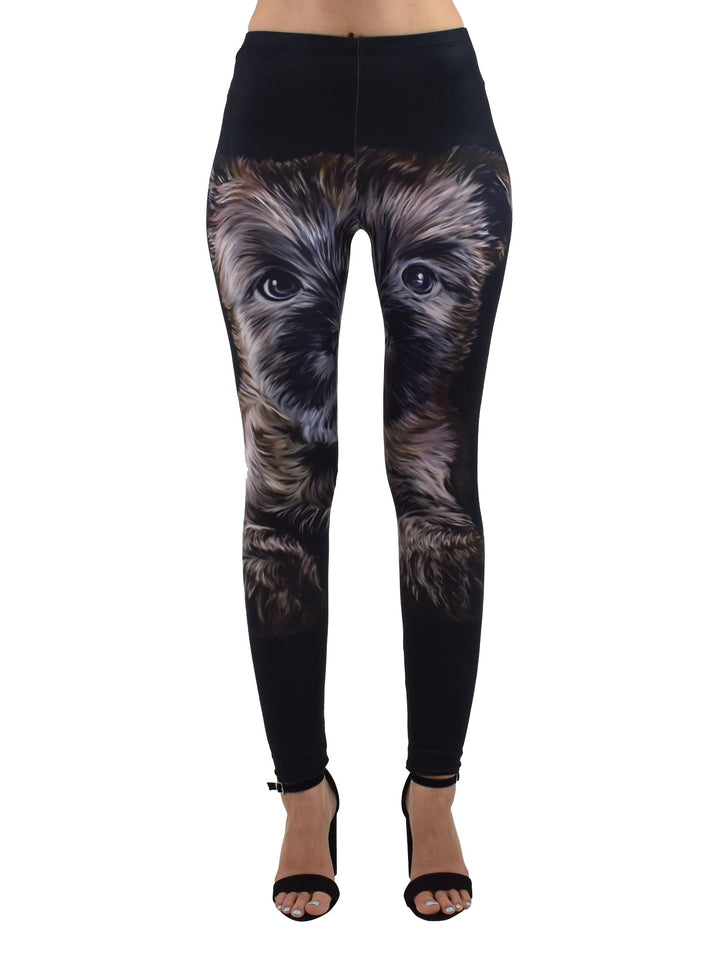 Front view of Denimaxx Cairn Terrier puppy print leggings with the shaggy puppy face spanning the legs on black fabric, modeled with sandals.